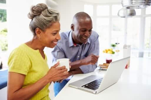 A woman having a coffee and a man watching something in the laptop